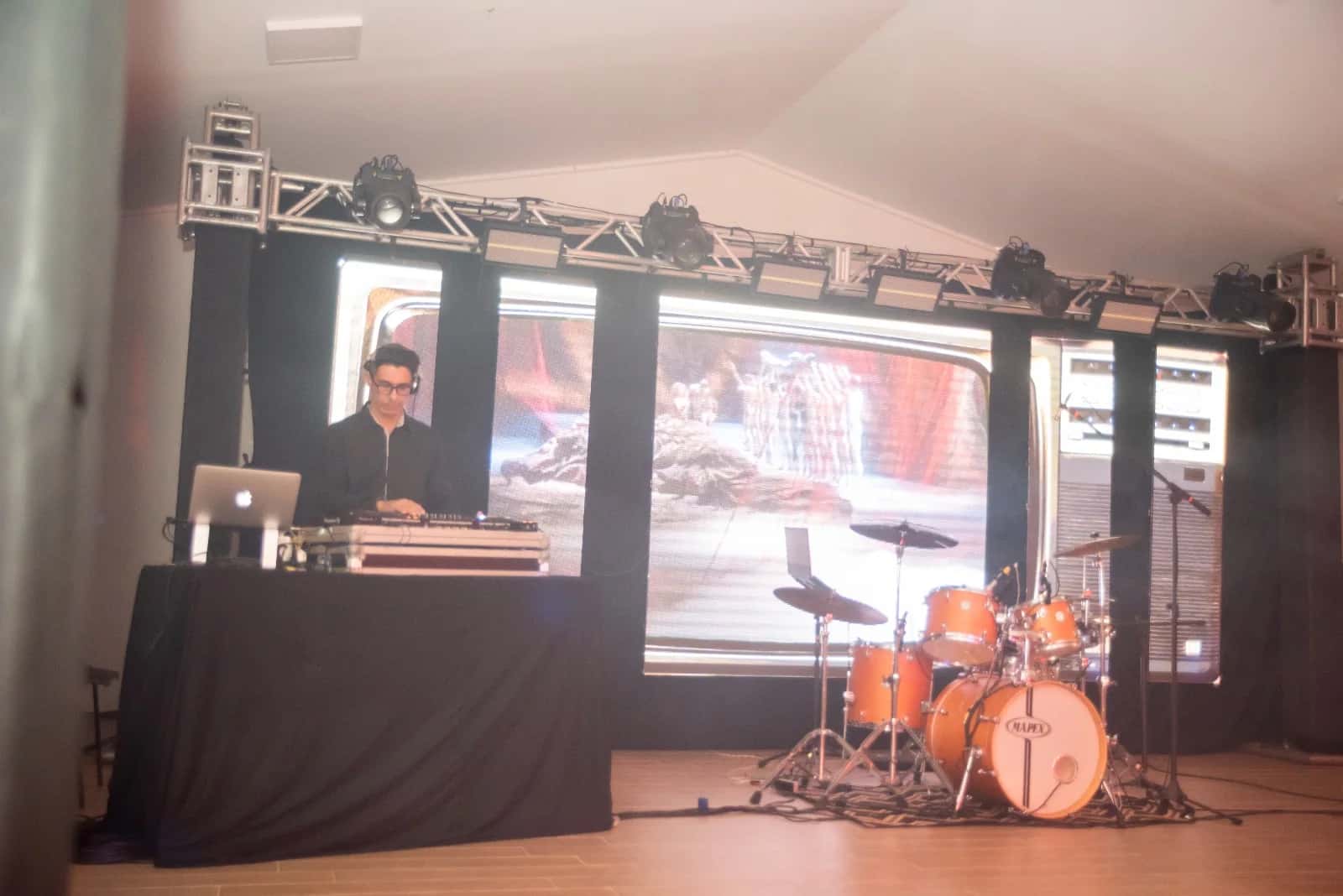 Palco do DJ BetoBrizz diante de telões de LED em formato de TVs retrô